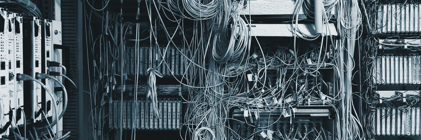 Densely packed equipment cabinets with unmanaged cabling running between them.